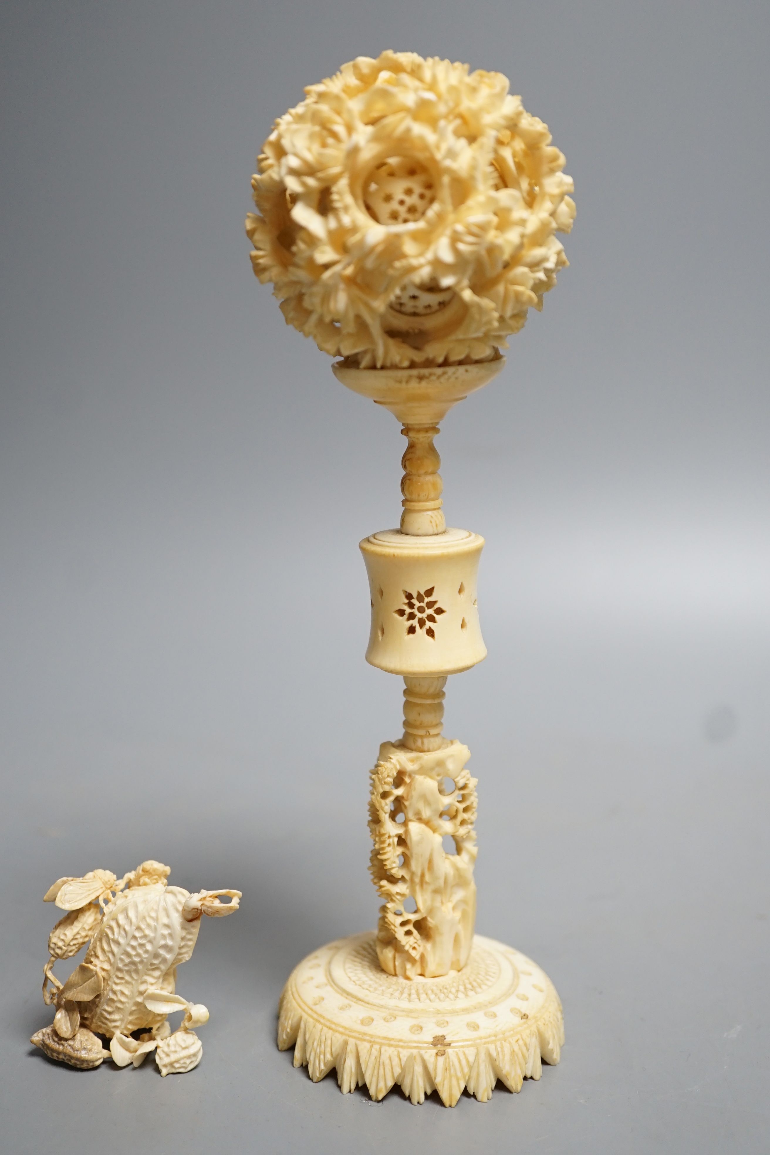 A Chinese ivory concentric puzzle ball and stand, two Chinese ivory snuff bottles and stoppers, modelled as a leaping carp and as cicadas on a nut, early 20th century